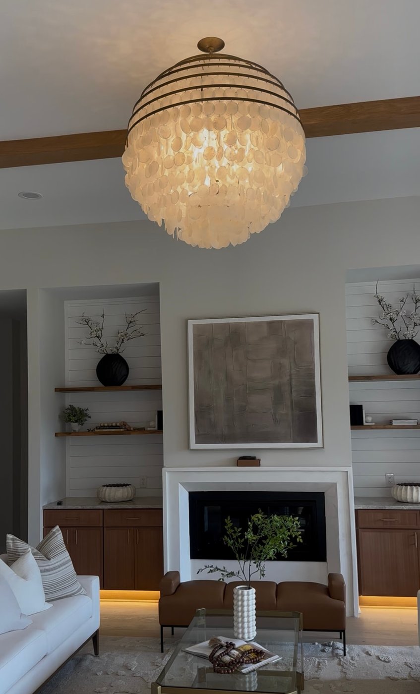 Capiz shell chandelier glowing above a living room fireplace