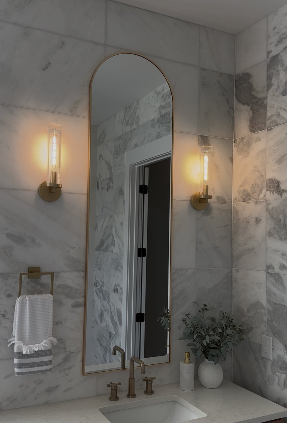Two bathroom sconces flanking an arched mirror